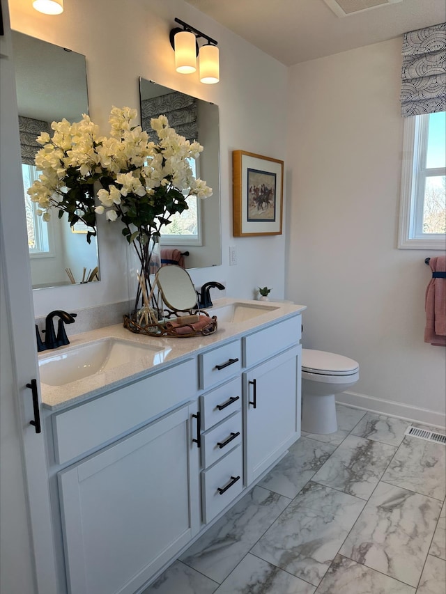 14536 74th St NE, Otsego, MN 55330 - bathroom with marble finish flooring, toilet, double vanity, and baseboards