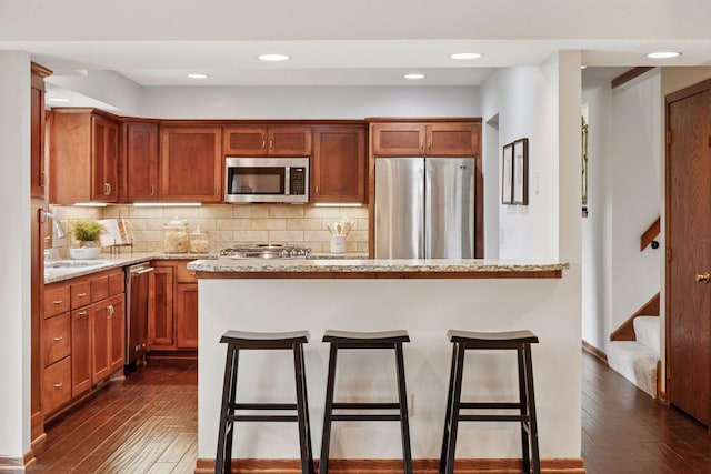 3291 Hillsboro Ave S, Saint Louis Park, MN 55426 - kitchen with stainless steel appliances, dark wood finished floors, a kitchen breakfast bar, decorative backsplash, and light stone countertops