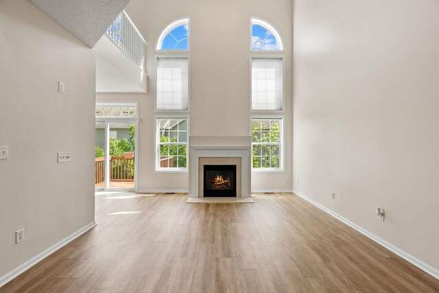 1353 White Oak Dr, Chaska, MN 55318 - unfurnished living room featuring a high ceiling, wood finished floors, plenty of natural light, and baseboards