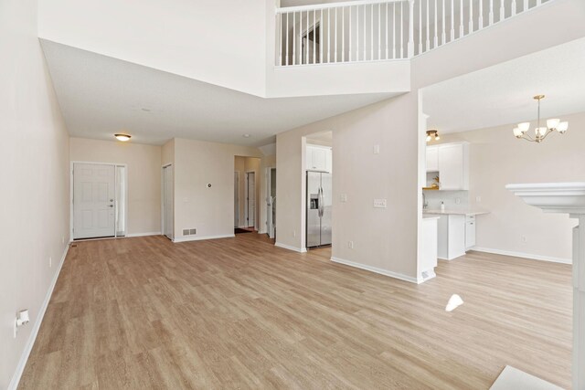 1353 White Oak Dr, Chaska, MN 55318 - unfurnished living room with light wood-style flooring, a chandelier, and baseboards