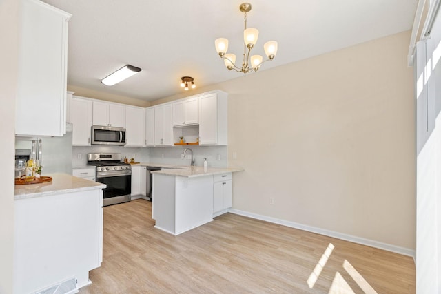 1353 White Oak Dr, Chaska, MN 55318 - kitchen with stainless steel appliances, light wood-style flooring, a peninsula, and white cabinets