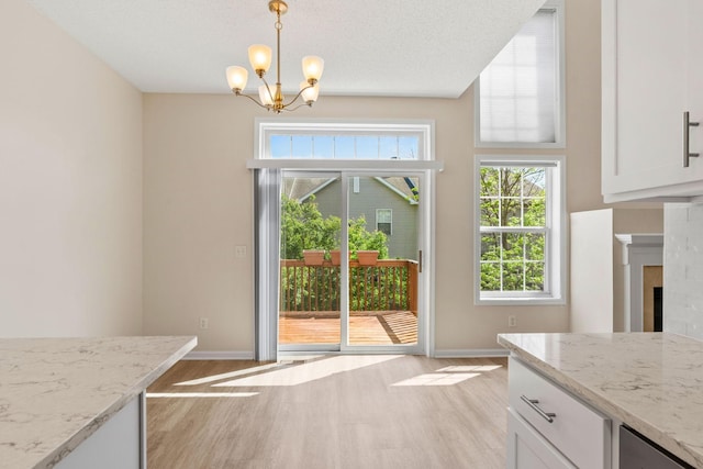 1353 White Oak Dr, Chaska, MN 55318 - unfurnished dining area with light wood-style floors, a chandelier, baseboards, and a tiled fireplace