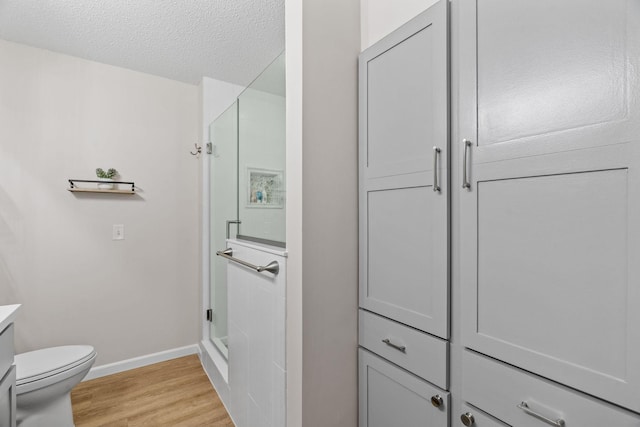 1353 White Oak Dr, Chaska, MN 55318 - bathroom with a shower stall, baseboards, wood finished floors, vanity, and toilet