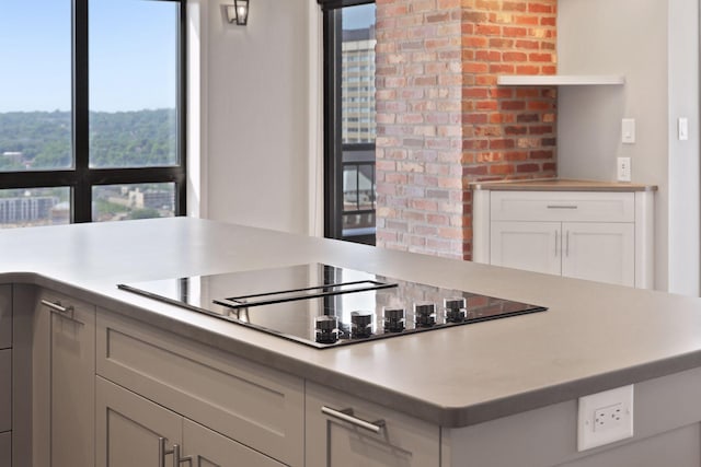 kitchen featuring black electric stovetop, light countertops, and white cabinets