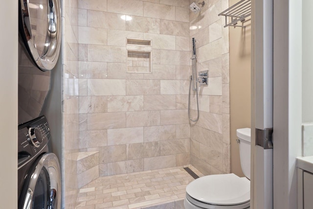 bathroom featuring stacked washer and clothes dryer, toilet, and tiled shower