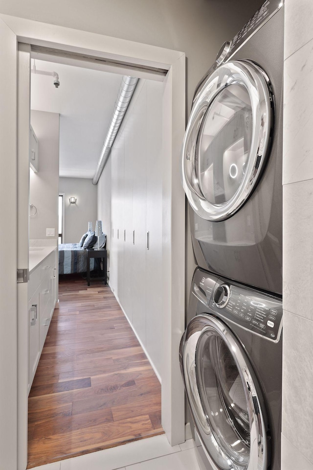 laundry area with stacked washing machine and dryer and wood finished floors