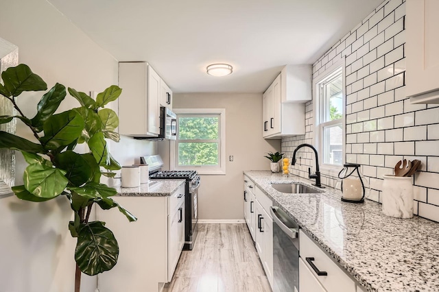 6670 Hopi Rd, Chanhassen, MN 55317 - kitchen featuring stainless steel appliances, a sink, backsplash, light stone counters, and white cabinetry