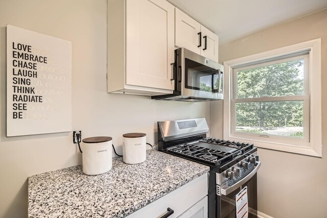 6670 Hopi Rd, Chanhassen, MN 55317 - kitchen featuring appliances with stainless steel finishes, light stone counters, and white cabinetry