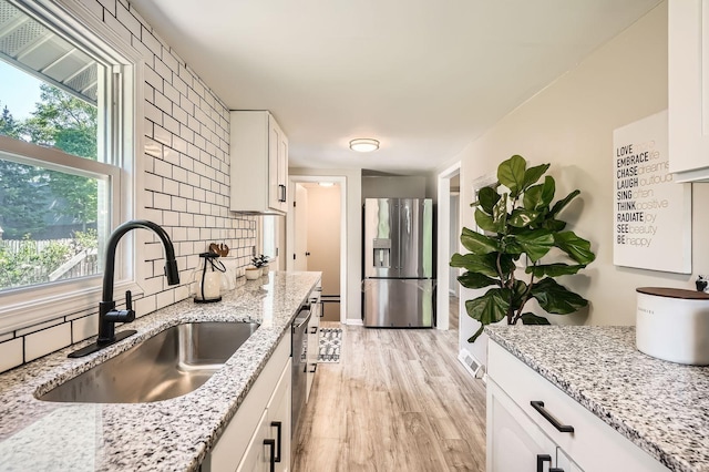 6670 Hopi Rd, Chanhassen, MN 55317 - kitchen featuring stainless steel appliances, a sink, light wood-style floors, white cabinets, and light stone countertops