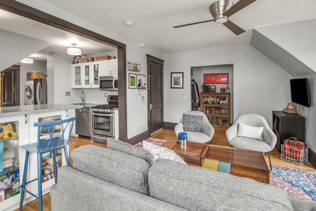 living area with washer / dryer, a ceiling fan, and light wood-style flooring