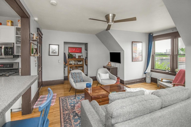 living area featuring a ceiling fan, baseboards, and light wood-style flooring