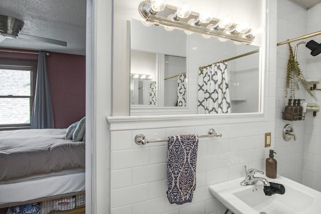 full bath featuring connected bathroom, a sink, a shower with shower curtain, and a textured ceiling