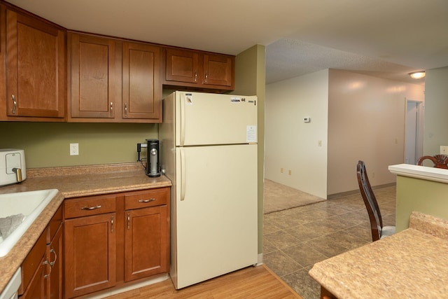 207 5th Ave SW Unit 407, Rochester, MN 55902 - kitchen featuring freestanding refrigerator, brown cabinetry, light countertops, and a sink
