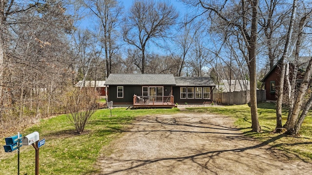 ranch-style home with a deck, roof with shingles, and driveway