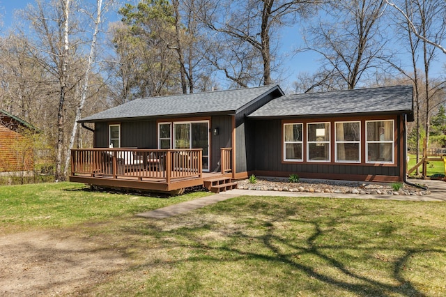 rear view of house featuring a shingled roof, a yard, and a wooden deck