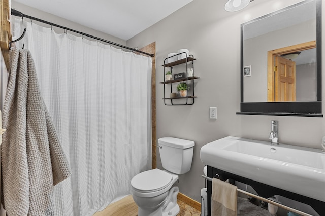 full bathroom with toilet, a sink, curtained shower, and baseboards