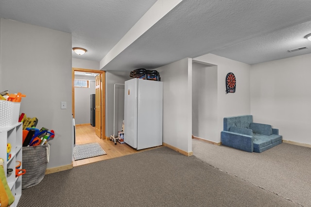 finished basement featuring baseboards, freestanding refrigerator, and carpet flooring