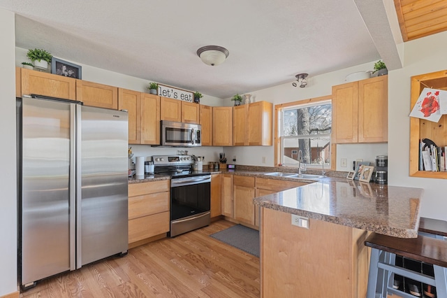 30432 Pinewood Dr, Breezy Point, MN 56472 - kitchen featuring appliances with stainless steel finishes, a sink, a peninsula, light wood-type flooring, and a breakfast bar area