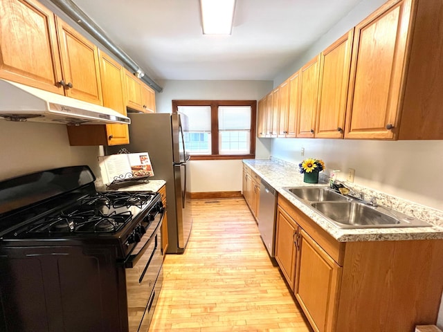 kitchen featuring black gas stove, under cabinet range hood, a sink, dishwasher, and light wood-type flooring
