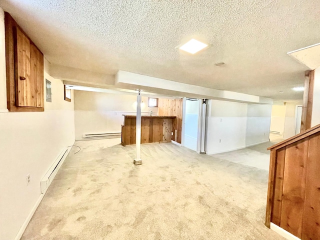 finished basement featuring baseboard heating, a textured ceiling, carpet, and bar
