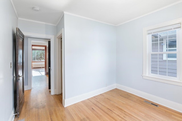 unfurnished room with light wood-style flooring, baseboards, a smoke detector, crown molding, and radiator heating unit