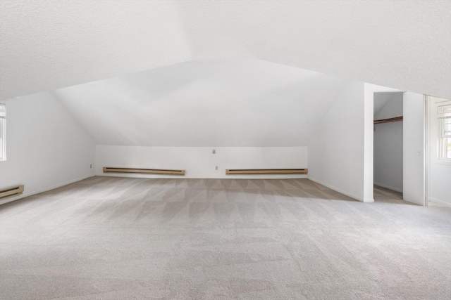 bonus room with a baseboard heating unit, light colored carpet, lofted ceiling, and baseboards