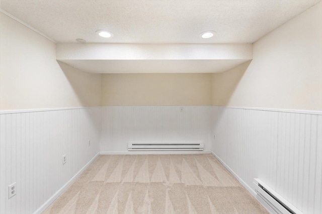 carpeted empty room featuring a baseboard heating unit, wainscoting, a textured ceiling, and recessed lighting