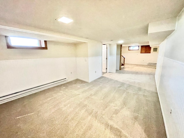below grade area featuring a baseboard radiator, wainscoting, light carpet, and stairway