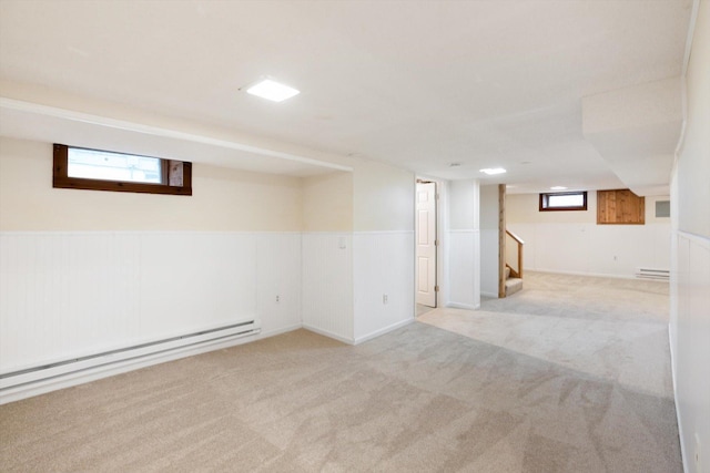 below grade area with baseboard heating, carpet, a wainscoted wall, stairs, and a baseboard heating unit