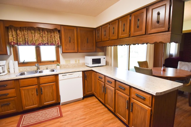 13946 151st St NE, Thief River Falls, MN 56701 - kitchen featuring white appliances, a sink, a peninsula, light countertops, and light wood-style flooring