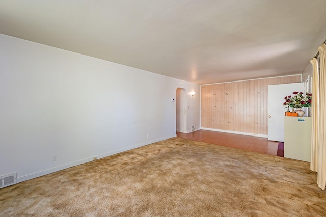 1202 Webster St, Fairmont, MN 56031 - carpeted empty room with arched walkways, baseboards, and wood walls