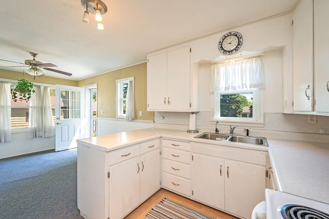 1202 Webster St, Fairmont, MN 56031 - kitchen with a sink, a peninsula, white cabinetry, light countertops, and a ceiling fan