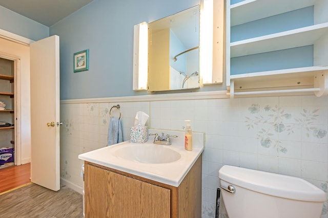 1202 Webster St, Fairmont, MN 56031 - bathroom with wood finished floors, wainscoting, toilet, vanity, and tile walls