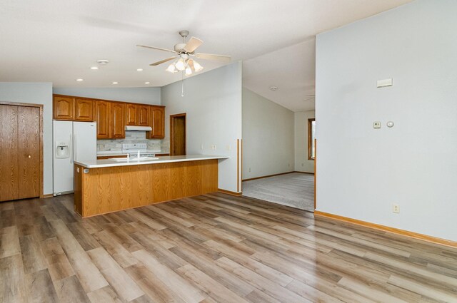 202 6th St NE, Montgomery, MN 56069 - kitchen featuring white refrigerator with ice dispenser, vaulted ceiling, a peninsula, a ceiling fan, and light countertops