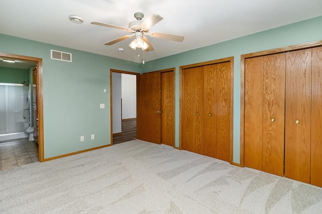 202 6th St NE, Montgomery, MN 56069 - unfurnished bedroom featuring two closets, baseboards, ensuite bathroom, carpet floors, and a ceiling fan