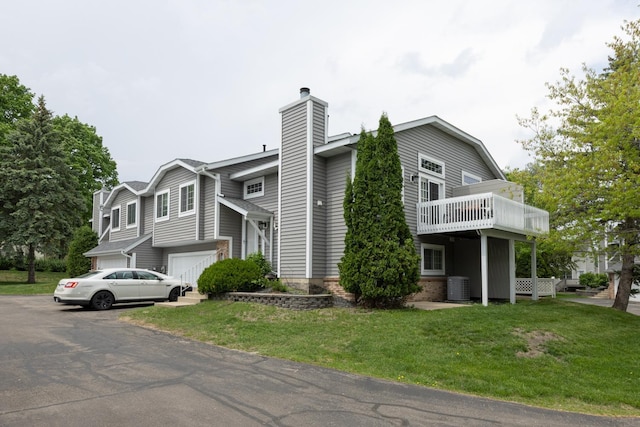 view of side of property featuring central air condition unit, a chimney, a yard, an attached garage, and driveway