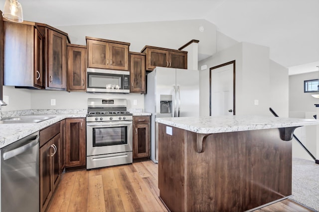1311 Jasmine Ln NE, Saint Joseph, MN 56374 - kitchen featuring stainless steel appliances, vaulted ceiling, light wood-style flooring, a sink, and a kitchen bar