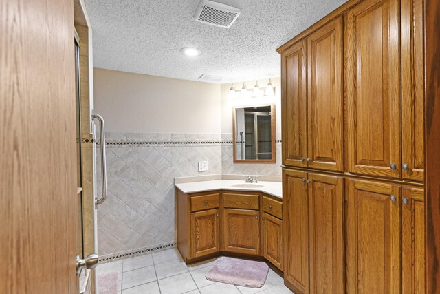 2403 Goettens Way, Saint Cloud, MN 56301 - bathroom with vanity, tile patterned flooring, tile walls, a shower with shower door, and a textured ceiling