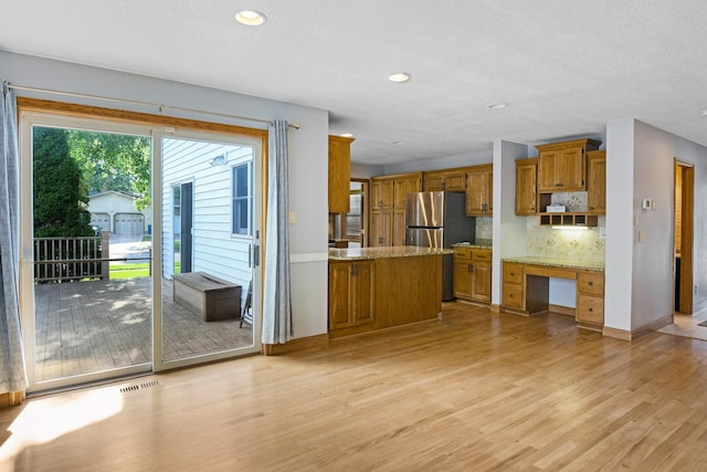2403 Goettens Way, Saint Cloud, MN 56301 - kitchen with brown cabinets, freestanding refrigerator, light wood finished floors, tasteful backsplash, and recessed lighting