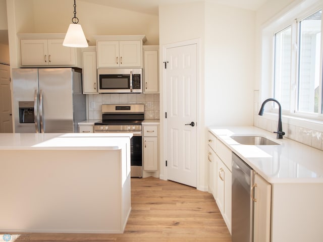 10302 Burgundy Dr, Horace, ND 58047 - kitchen with stainless steel appliances, a sink, decorative backsplash, light wood-style flooring, and pendant lighting