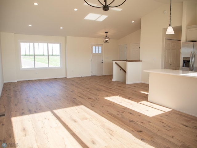 10302 Burgundy Dr, Horace, ND 58047 - unfurnished living room with light wood-style floors, recessed lighting, vaulted ceiling, baseboards, and a chandelier