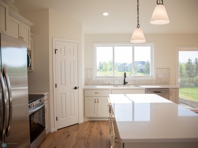 10302 Burgundy Dr, Horace, ND 58047 - kitchen featuring stainless steel appliances, a sink, a center island, decorative backsplash, and light wood finished floors