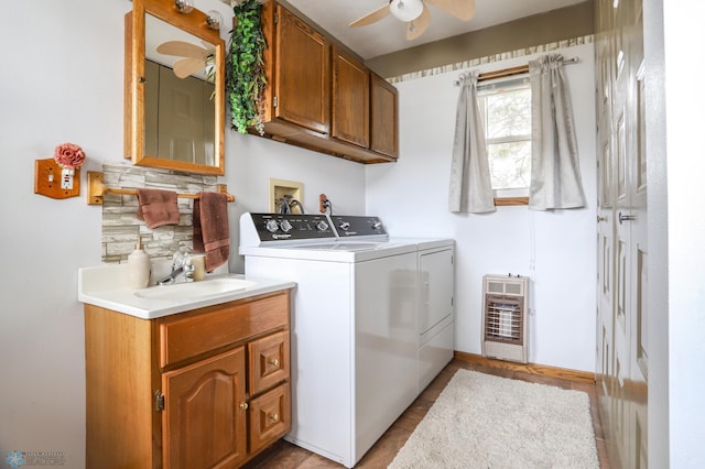 laundry room featuring washing machine and clothes dryer, cabinet space, a ceiling fan, heating unit, and baseboards