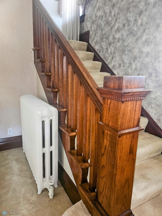 stairway with radiator, carpet floors, and wallpapered walls