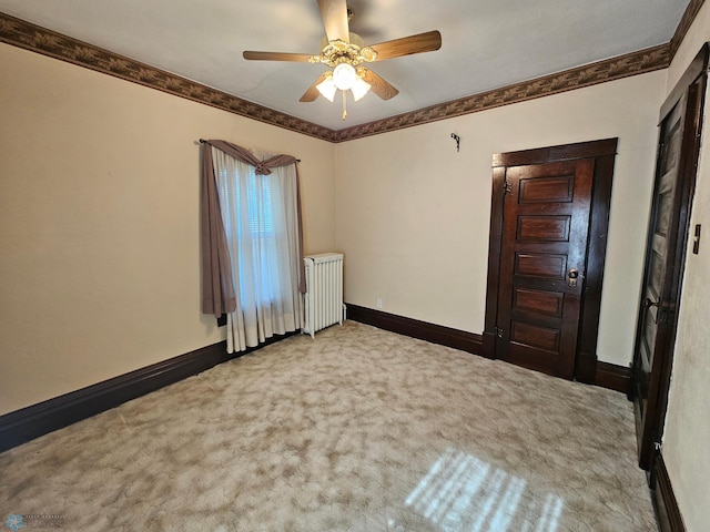 carpeted spare room featuring radiator heating unit, baseboards, and ceiling fan