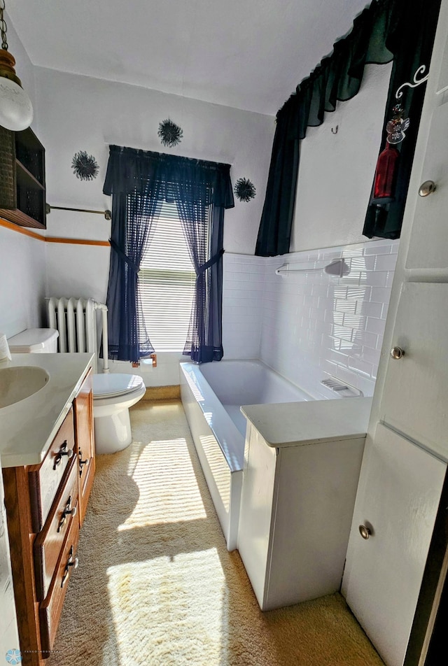 full bath featuring radiator, a bath, vanity, and toilet
