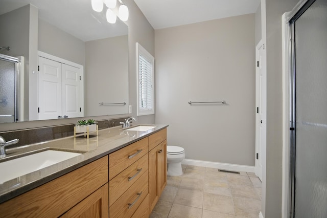bathroom featuring a shower stall, baseboards, toilet, double vanity, and tile patterned flooring