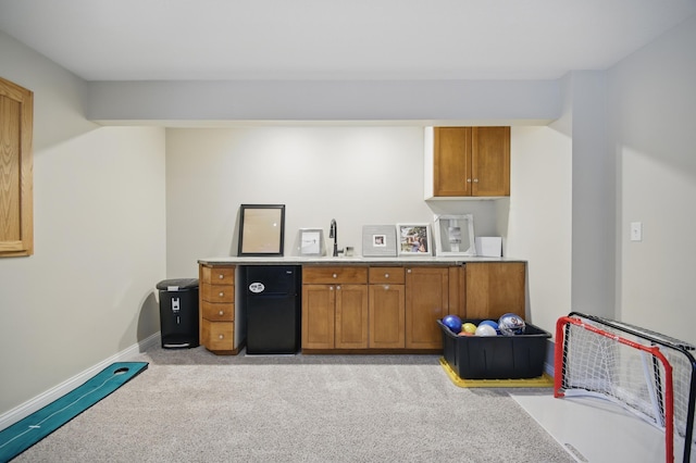 indoor wet bar featuring light carpet and baseboards