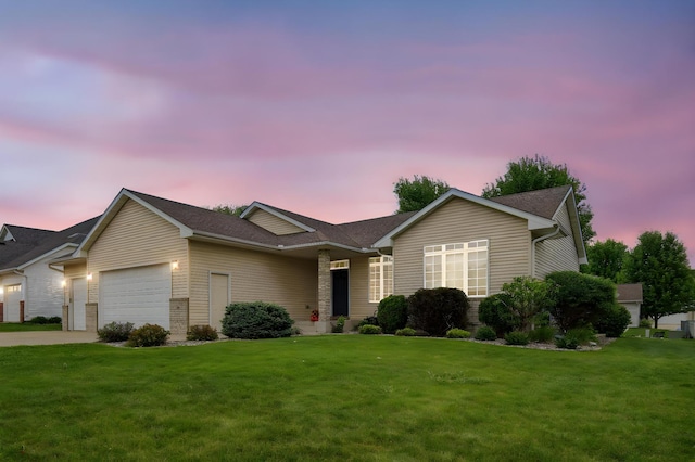 ranch-style house featuring an attached garage, a front yard, driveway, and a shingled roof