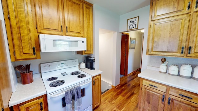 kitchen featuring white appliances, light countertops, light wood-type flooring, and brown cabinets
